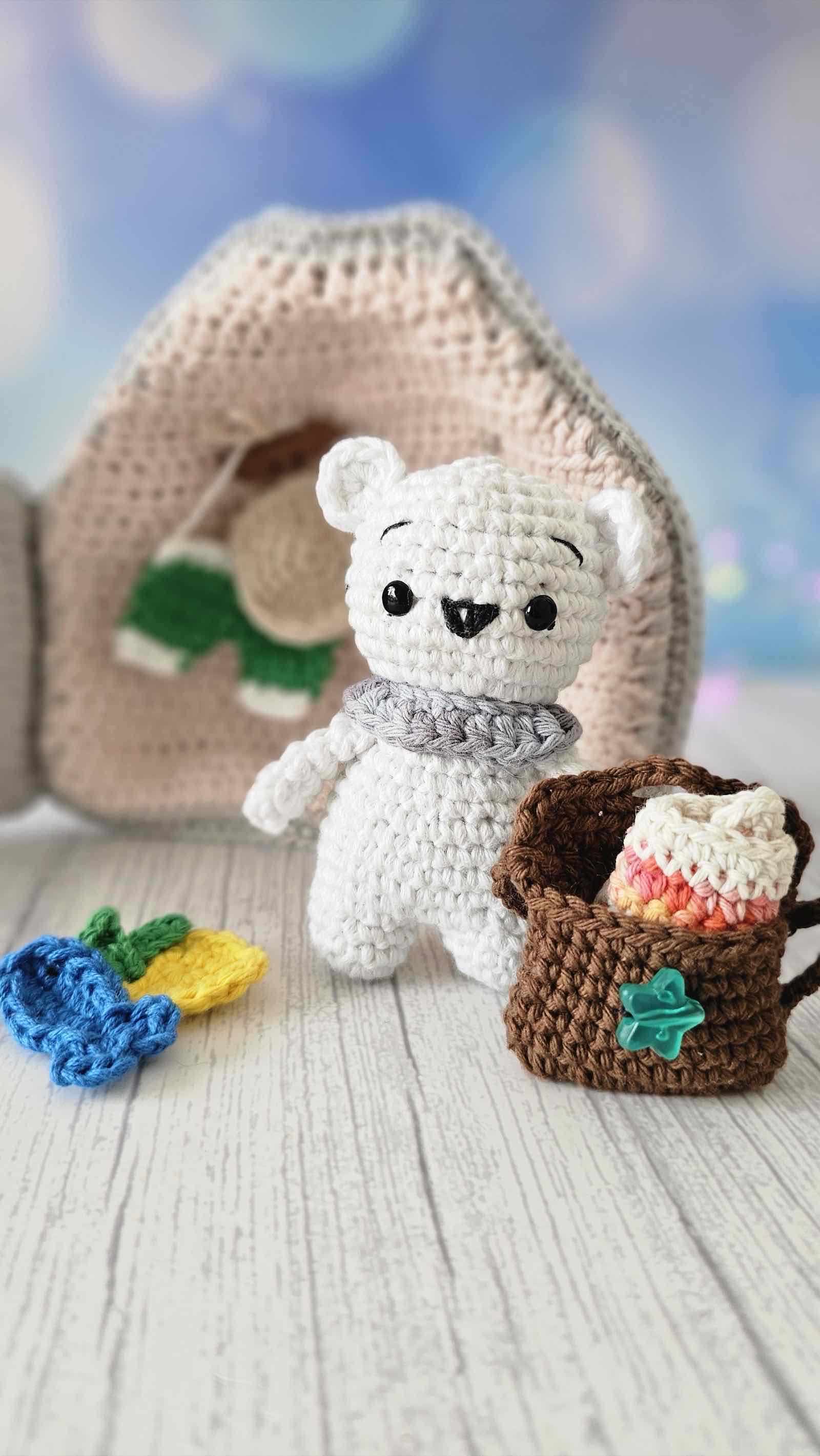 Osito amigurumi frente a la página del Quiet Book con mochila de playa